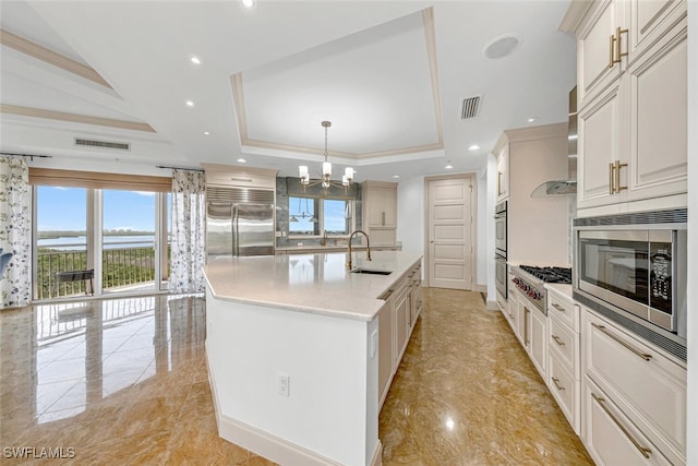 kitchen featuring built in appliances, a tray ceiling, a sink, and visible vents