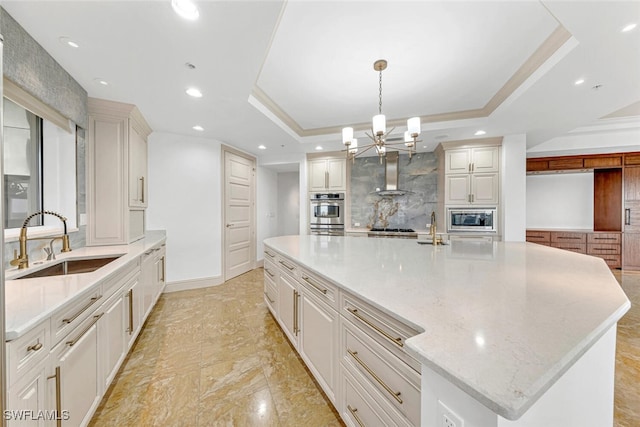 kitchen featuring a sink, tasteful backsplash, stainless steel appliances, wall chimney exhaust hood, and a raised ceiling