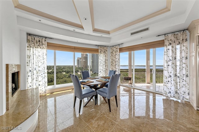 dining room with a premium fireplace, visible vents, marble finish floor, a tray ceiling, and crown molding