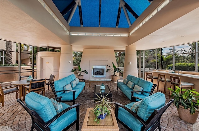 view of patio / terrace with glass enclosure, outdoor dining space, and an outdoor living space with a fireplace