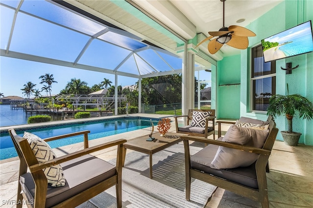 view of swimming pool with a patio area, a lanai, a water view, and ceiling fan