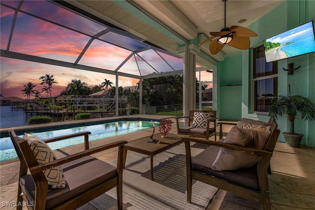 pool at dusk with ceiling fan, a lanai, outdoor lounge area, and a patio area