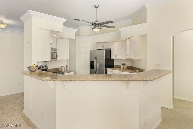 kitchen with kitchen peninsula, ornamental molding, white cabinets, and stainless steel appliances