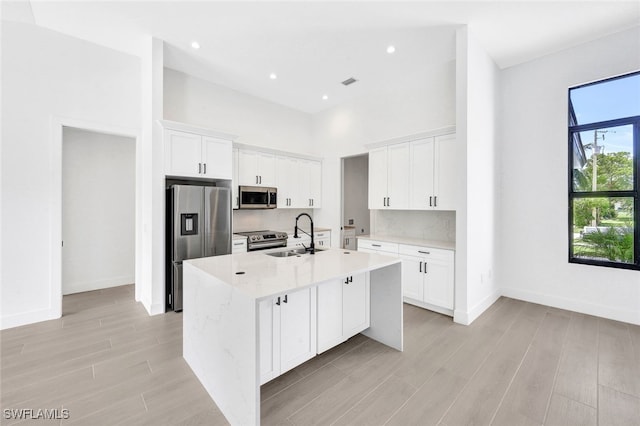 kitchen featuring backsplash, white cabinetry, light stone countertops, sink, and stainless steel appliances