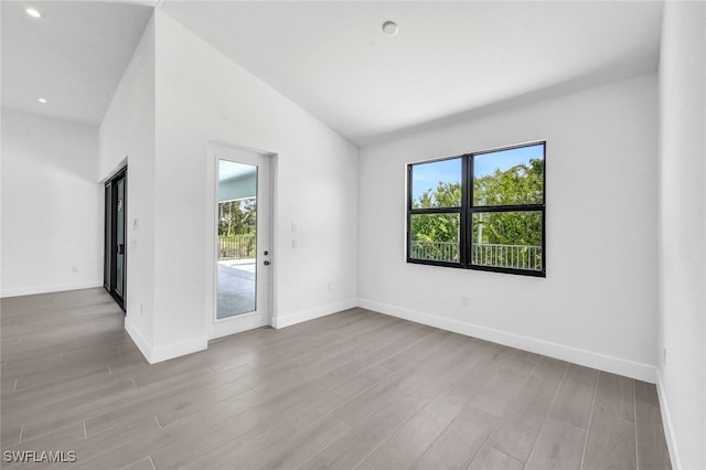 unfurnished room featuring lofted ceiling and hardwood / wood-style floors