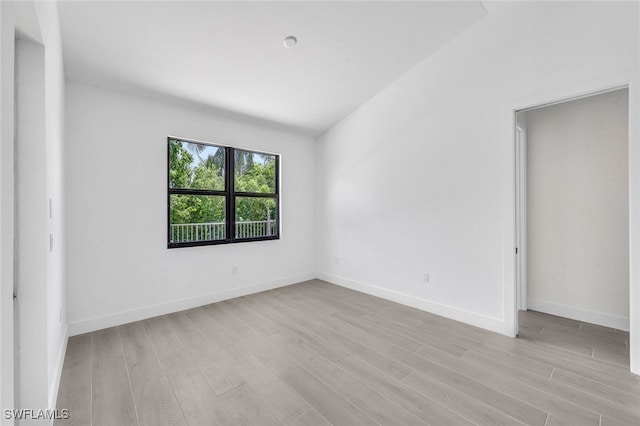 unfurnished room featuring light hardwood / wood-style floors and vaulted ceiling