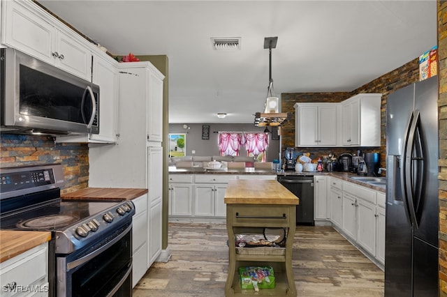 kitchen with stainless steel appliances, wood counters, decorative light fixtures, and light hardwood / wood-style flooring