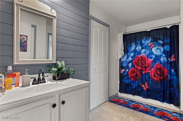 bathroom featuring tile patterned floors, wood walls, and vanity