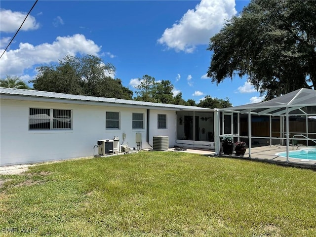 back of property with a lanai, a yard, and central AC unit