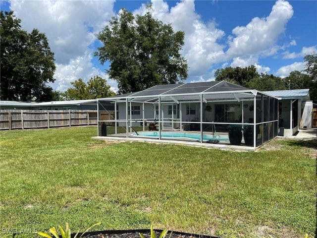 rear view of house with a fenced in pool, glass enclosure, and a lawn