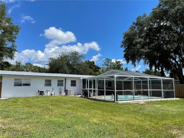 rear view of property featuring a lanai, a yard, and cooling unit