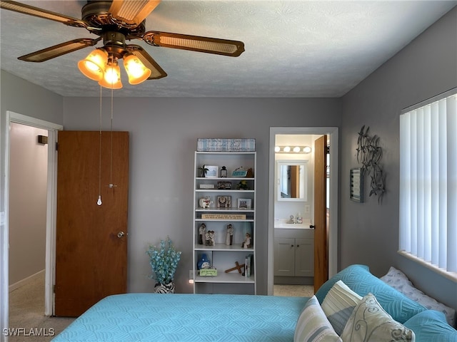 carpeted bedroom with ceiling fan, ensuite bathroom, sink, and a textured ceiling