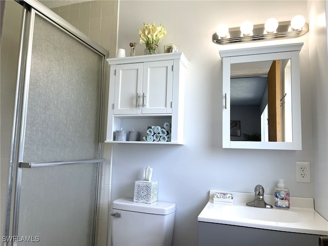 bathroom with toilet, vanity, and a shower with shower door