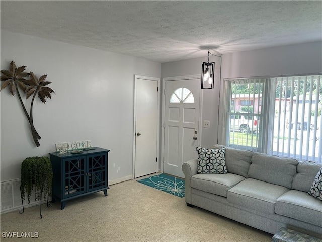 living room with an inviting chandelier and a textured ceiling