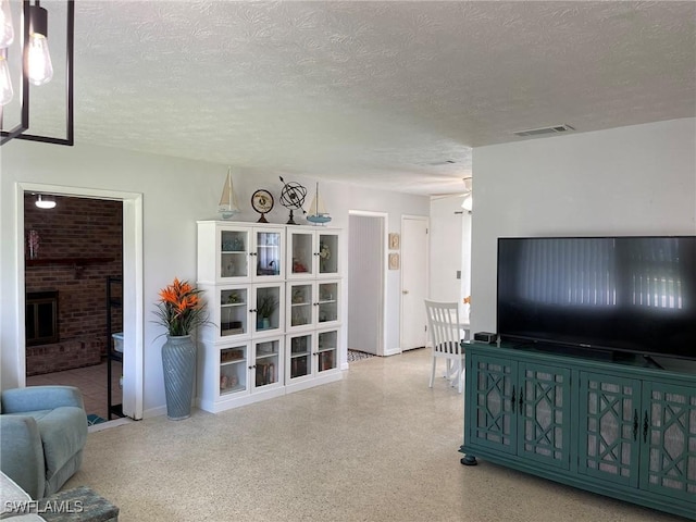 living room featuring a brick fireplace and a textured ceiling