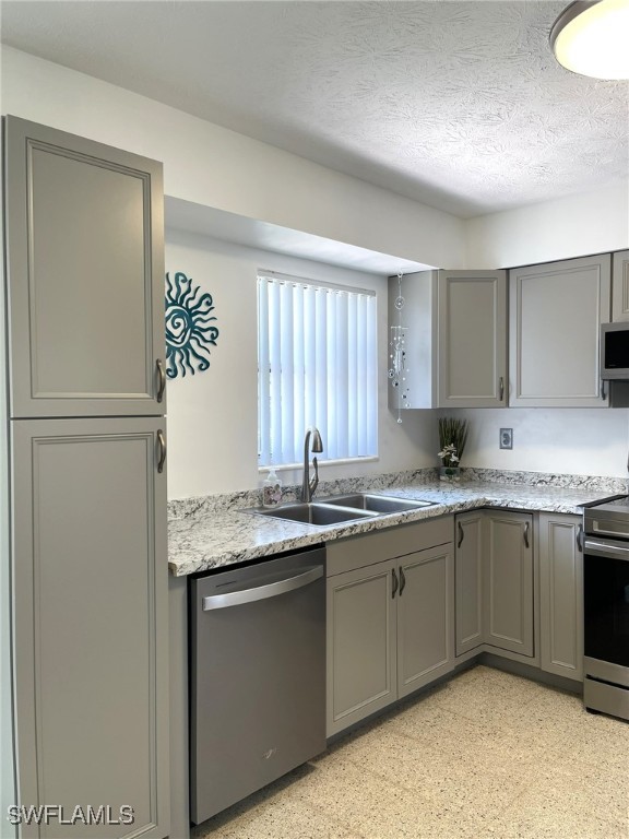 kitchen with sink, stainless steel appliances, gray cabinets, and a textured ceiling