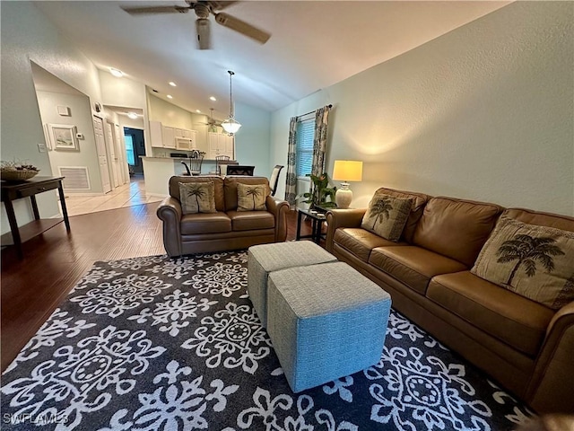 living room with light hardwood / wood-style flooring, vaulted ceiling, and ceiling fan