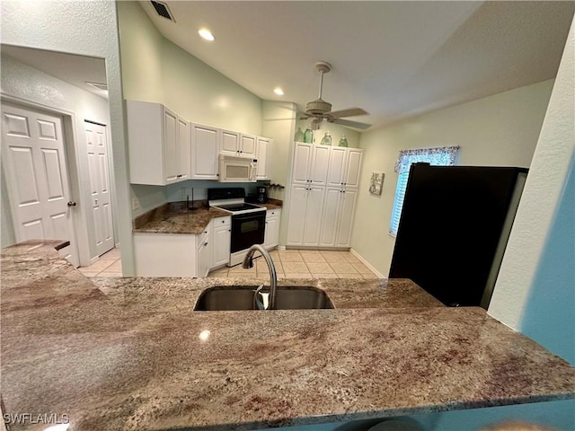 kitchen featuring range with electric cooktop, white cabinets, white microwave, a peninsula, and a sink