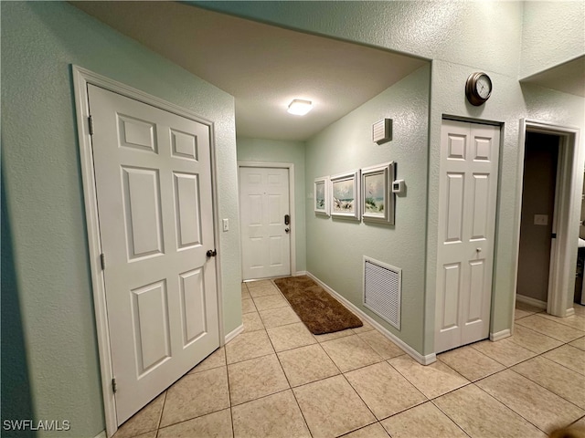 corridor featuring light tile patterned floors and a textured ceiling