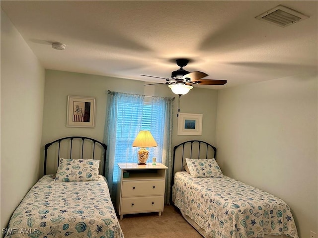 bedroom featuring a ceiling fan, visible vents, and light carpet