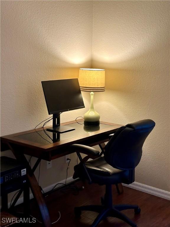 office with a textured wall, wood finished floors, and baseboards