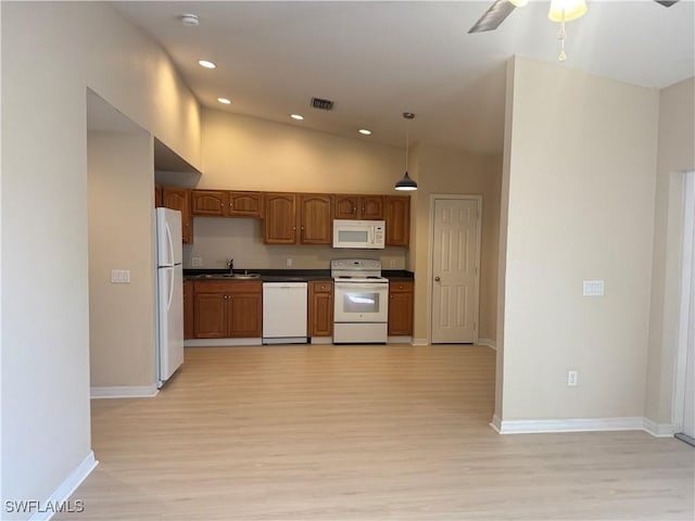 kitchen with sink, high vaulted ceiling, pendant lighting, white appliances, and light hardwood / wood-style floors