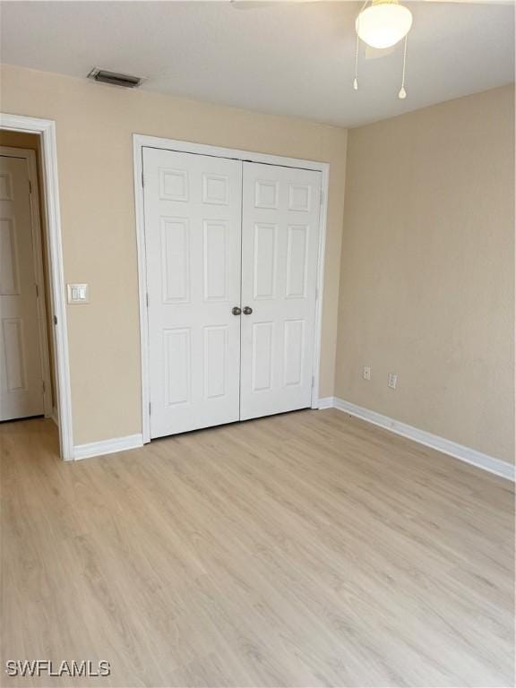 unfurnished bedroom with ceiling fan, a closet, and light wood-type flooring