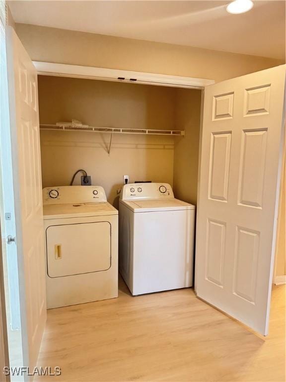 laundry room with independent washer and dryer and light hardwood / wood-style floors