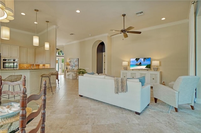 living area with arched walkways, recessed lighting, a ceiling fan, visible vents, and crown molding