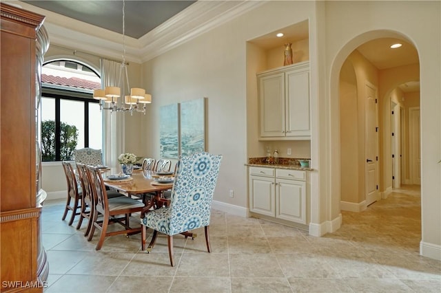 dining room with arched walkways, a notable chandelier, light tile patterned floors, ornamental molding, and baseboards