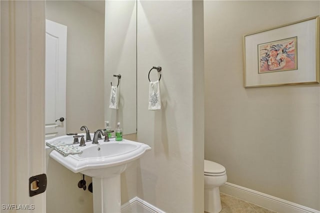 bathroom with toilet, tile patterned flooring, and baseboards