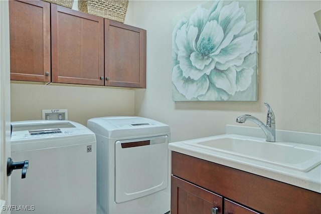 laundry area with a sink, washing machine and dryer, and cabinet space