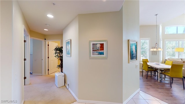 hall featuring a chandelier, recessed lighting, light tile patterned flooring, and baseboards