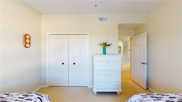 bedroom with a closet, light colored carpet, visible vents, and baseboards