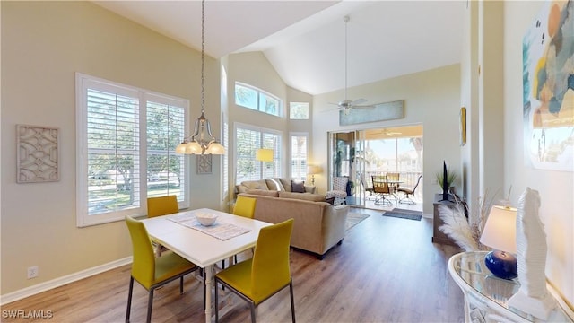 dining room featuring high vaulted ceiling, plenty of natural light, wood finished floors, and baseboards