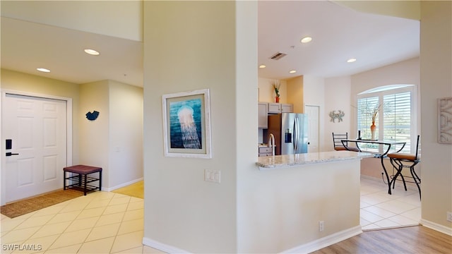 kitchen featuring light stone counters, recessed lighting, a sink, visible vents, and stainless steel fridge with ice dispenser