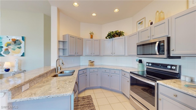 kitchen featuring decorative backsplash, appliances with stainless steel finishes, light tile patterned floors, sink, and kitchen peninsula