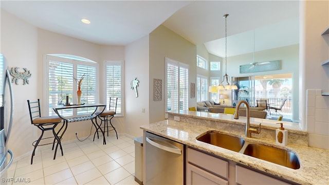 kitchen with sink, decorative light fixtures, appliances with stainless steel finishes, light stone countertops, and light tile patterned floors