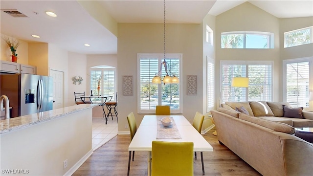 dining area featuring visible vents, a high ceiling, light wood-style flooring, and recessed lighting