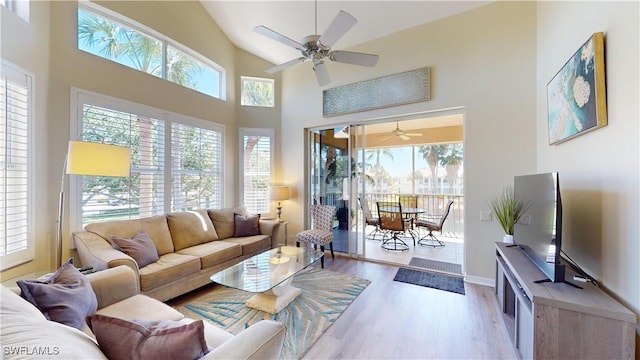 living room featuring baseboards, high vaulted ceiling, a ceiling fan, and light wood-style floors