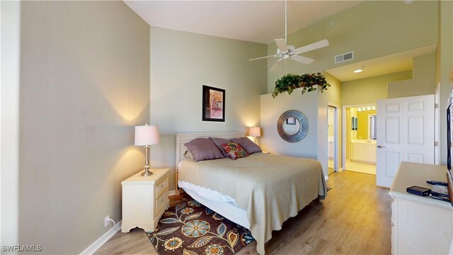 bedroom with visible vents, light wood-style flooring, connected bathroom, high vaulted ceiling, and baseboards