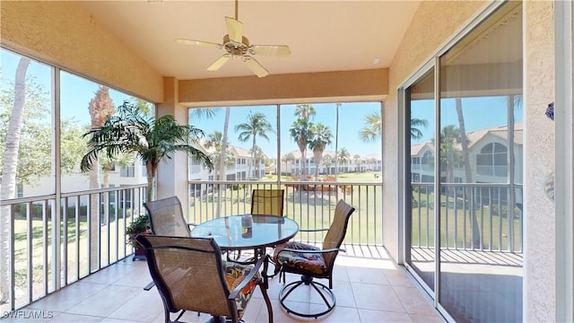 sunroom / solarium with plenty of natural light, a residential view, and a ceiling fan