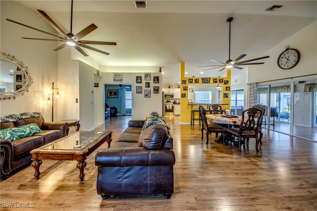 living room with hardwood / wood-style floors, high vaulted ceiling, and ceiling fan