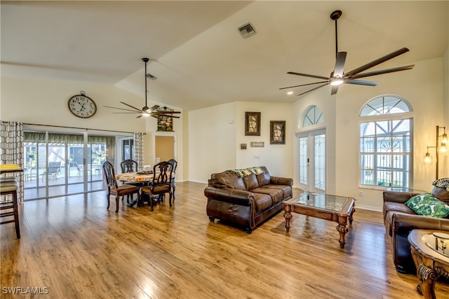 living room with ceiling fan, high vaulted ceiling, french doors, and light hardwood / wood-style floors