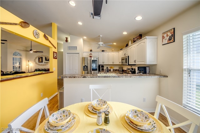 kitchen with ceiling fan, white cabinets, light stone counters, hardwood / wood-style flooring, and stainless steel appliances