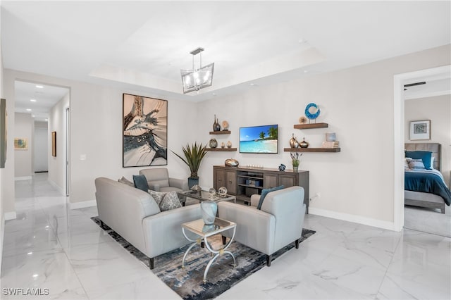 living room featuring a tray ceiling, a chandelier, and light tile patterned floors