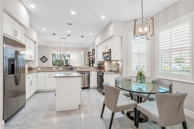 kitchen with light tile patterned floors, kitchen peninsula, stainless steel appliances, and a healthy amount of sunlight