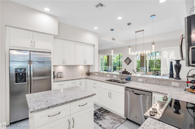 kitchen with light stone countertops, sink, kitchen peninsula, and stainless steel appliances