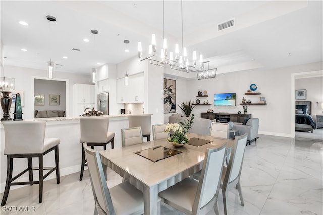 dining area with light tile patterned floors, a raised ceiling, and an inviting chandelier