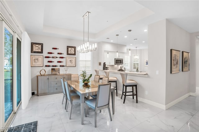 dining area featuring a tray ceiling, a chandelier, and light tile patterned floors